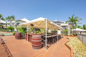 Un espace extérieur aménagé avec un patio, un barbecue, des sièges et une piscine en arrière-plan.