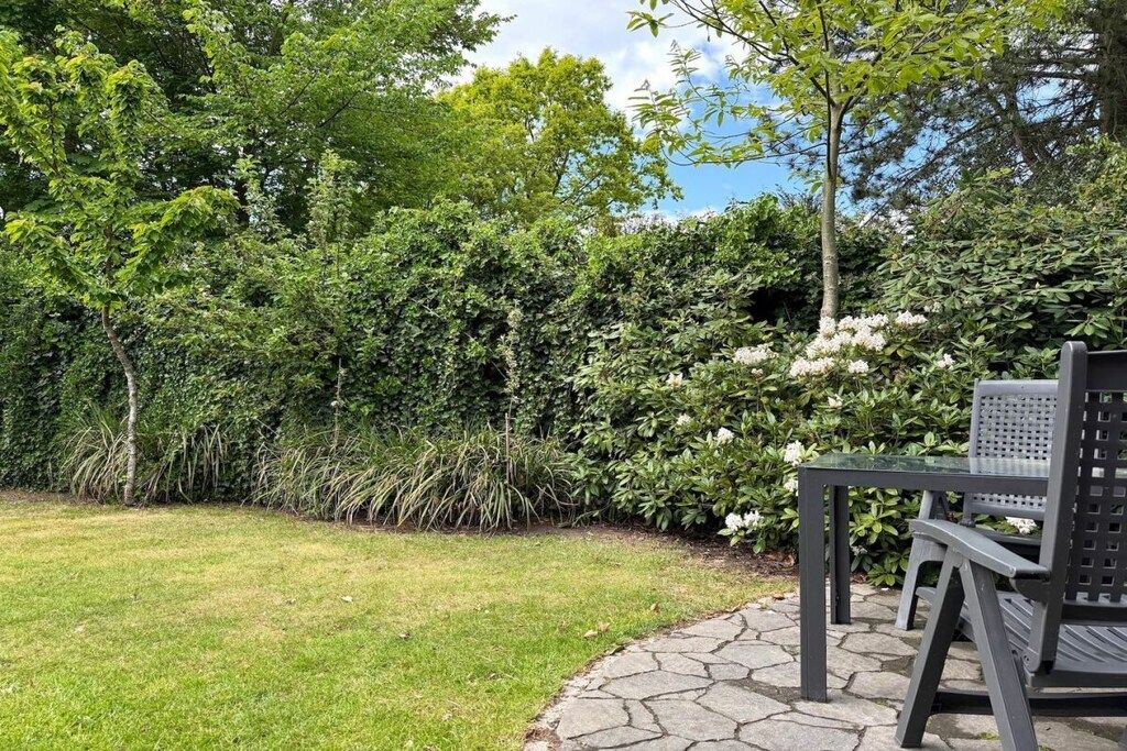 Un jardín con un sendero de piedra, una mesa y sillas.