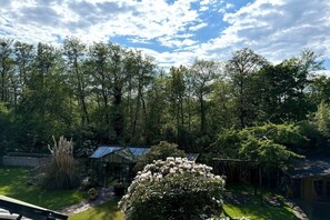 Ein Garten mit Gewächshaus, Bäumen und einer Schaukel.