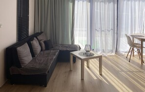 A modern living room with a sectional sofa, a small table, and a dining area with a chair. - Amazing home in Liniewo with house a panoramic view (Wielki Klincz)