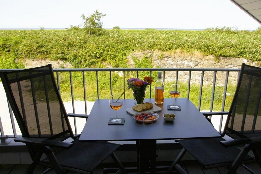 A table set for two with a view of a vineyard, a bottle of wine, and a glass of beer.