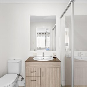 Un baño moderno con inodoro, lavamanos y zona de ducha.