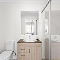 Un baño moderno con inodoro, lavamanos y zona de ducha.