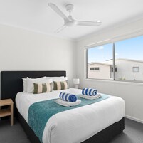 Habitación de hotel con cama, mesita de noche, ventana y ventilador de techo.