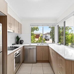 Una cocina moderna con armarios de madera, lavavajillas y vistas al vecindario.
