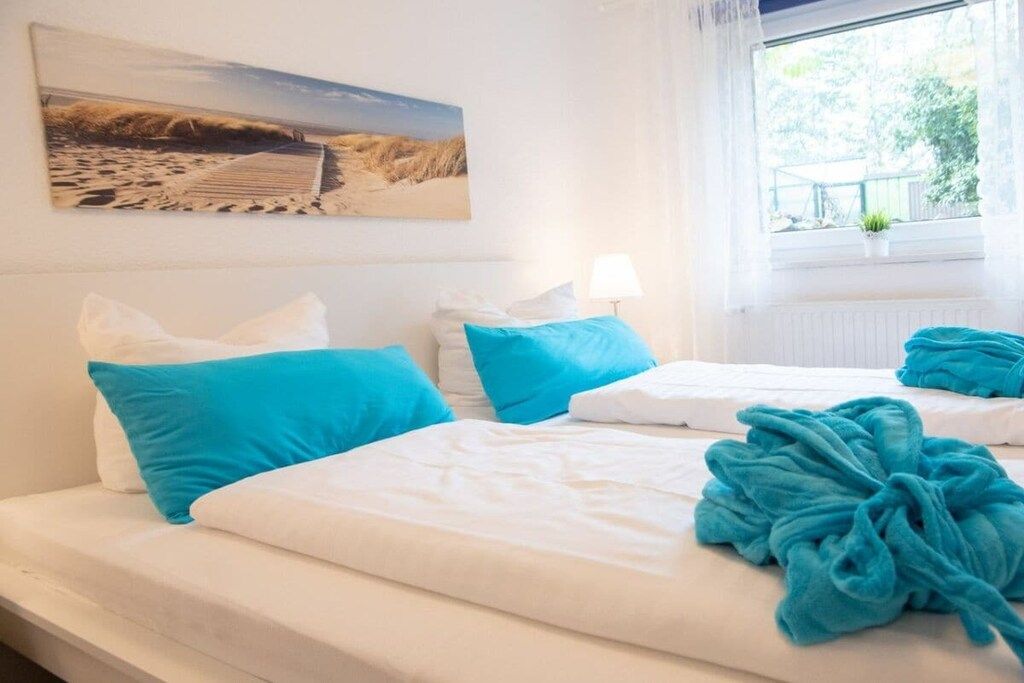 Ein Hotelzimmer mit Bett, Kissen, einem Fenster mit Aussicht und einem Bild an der Wand.