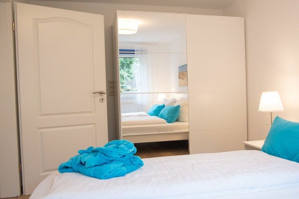 A hotel room with a bed, a bedside lamp, and a view through an open door.