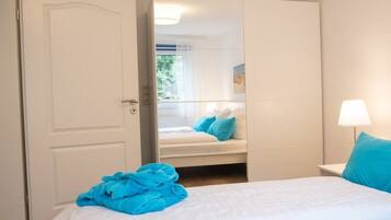 A hotel room with a bed, a bedside lamp, and a view through an open door.