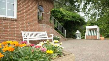 A brick building with a white bench and flower beds in the foreground.