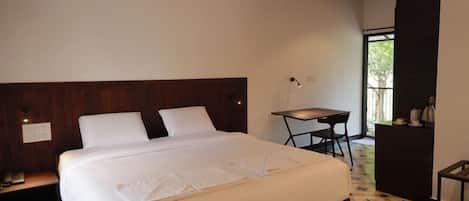 A hotel room with a large bed, a desk, and a chair.