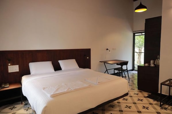 A hotel room with a large bed, a desk, and a chair.