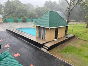 A small building with a green roof next to a swimming pool.