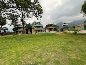 A hotel with multiple buildings, a swimming pool, and a grassy lawn. - Kava Eco Camp and Caravan Park (Palakkad)