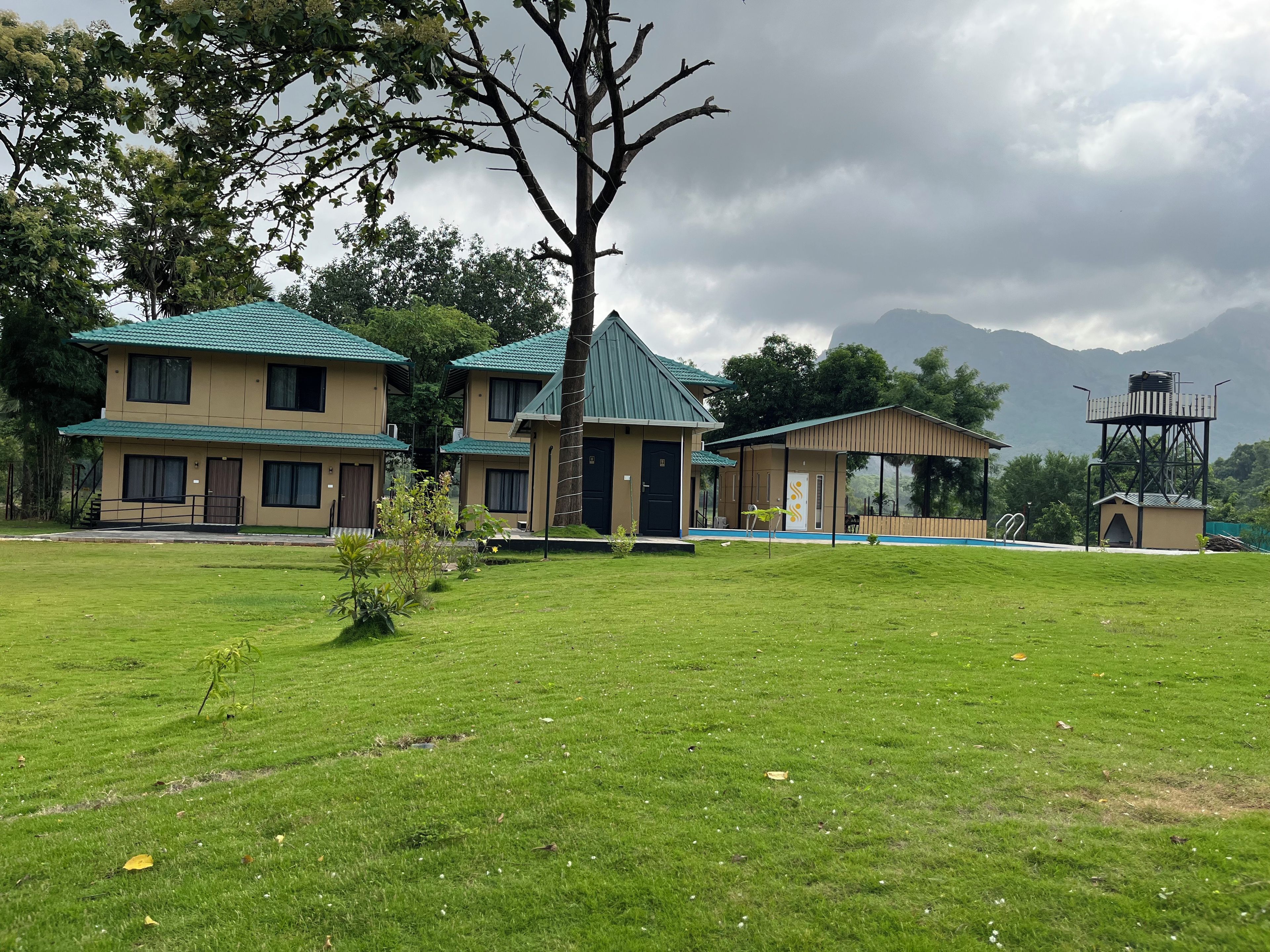 A hotel with multiple two-story buildings, a grassy lawn, and a mountain backdrop.