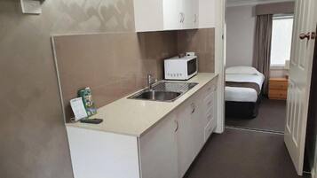 A compact kitchenette with a microwave, sink, and cabinets.