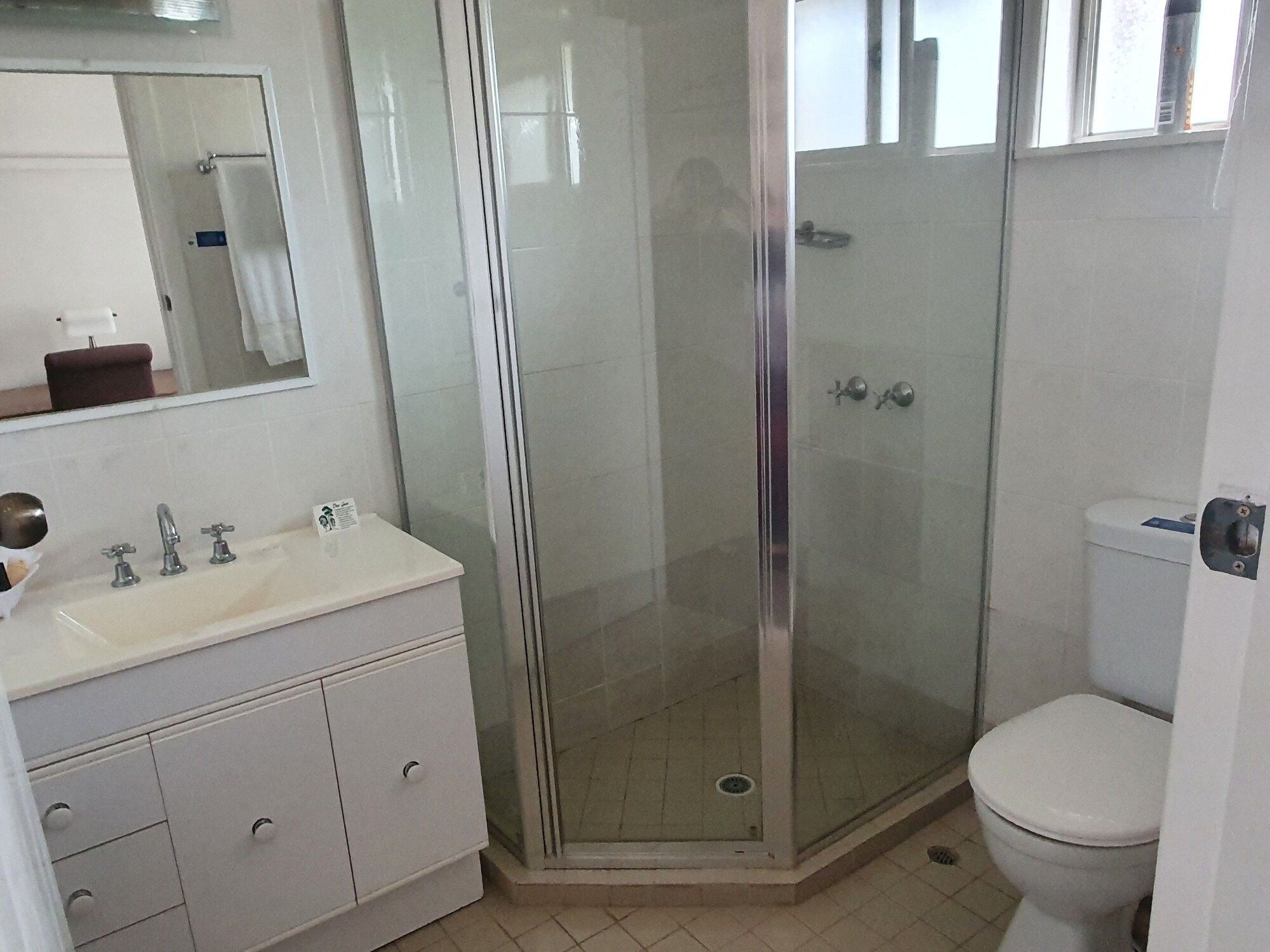 A bathroom with a glass-enclosed shower, a white sink with a mirror above it, and a toilet.