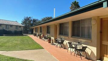 A motel with a patio area featuring outdoor seating and a well-maintained lawn.