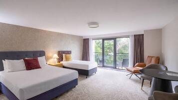 A hotel room with a large bed, a smaller bed, a desk, and a balcony with a view.