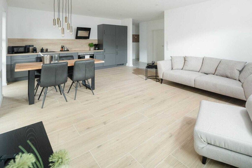 A modern living space with a dining area, a sofa, and a kitchen.