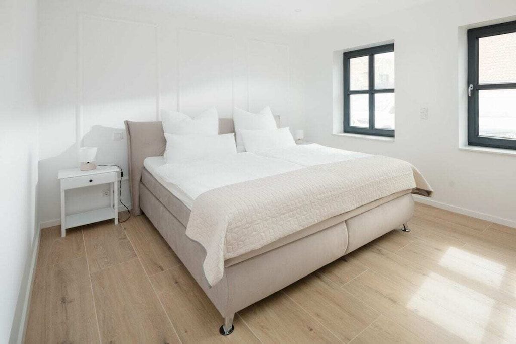A bedroom with a bed, a nightstand, and a window.