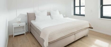 A bedroom with a bed, a nightstand, and a window.