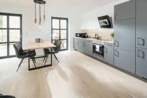 Eine moderne Küche mit grauen Schränken, einem Holztisch und einem eingebauten Backofen.