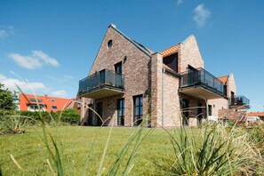A modern two-story house with a brick exterior, large windows, and balconies. - Coastal Suite South | Side Waterfront Location (Greetsiel, Germany)