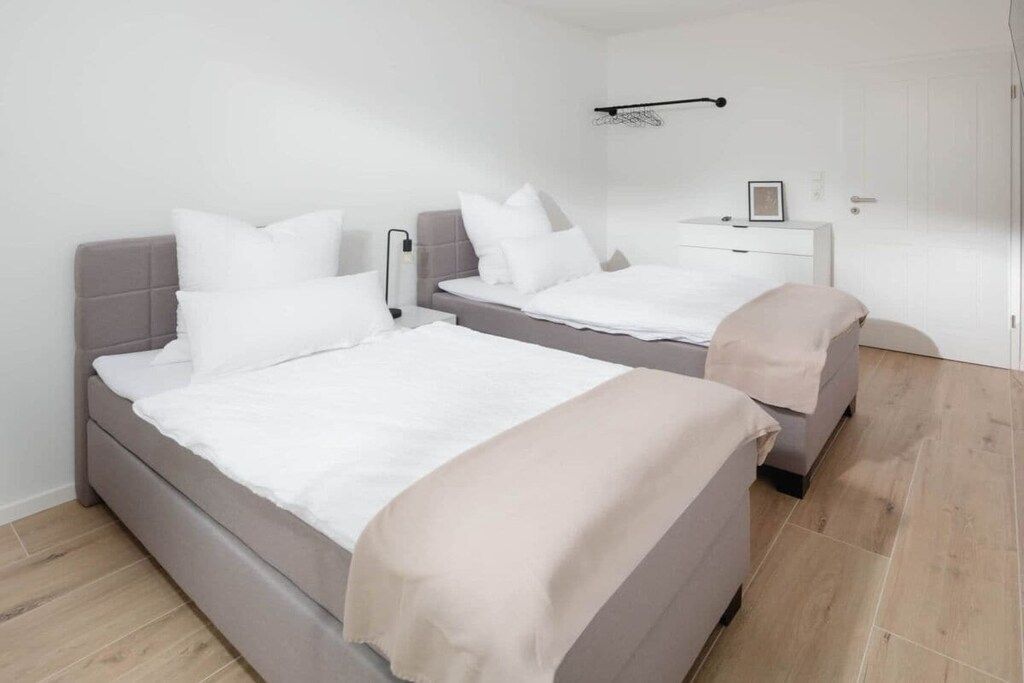 A bedroom with two beds, a bedside table, a nightstand, and a door.
