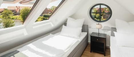 A bedroom with a skylight, a round mirror, and a view of a garden.