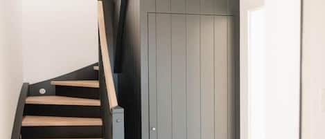 A staircase with wooden steps and a black railing leading to a grey door.
