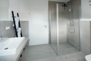 Un baño moderno con ducha envuelta en vidrio, una bañera blanca y un perchero para toallas.