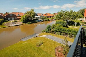 A residential area with houses, a river, and a grassy area with a dock. - Coastal Suite East | Directly on the waterfront (Greetsiel)