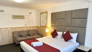 Una habitación de hotel con una cama, un sofá, una mesita de noche y un espejo.