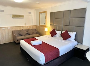 Habitació d'hotel amb un llit, un sofà, una taula de nit i un mirall.