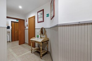 A hallway with wooden doors, a small table with a mirror, and framed pictures on the wall. - Holiday Home 'San Pietro House' with Balcony, Wi-Fi and Air Conditioning (Roma)