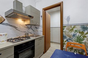 Eine kleine Küche mit einem Gasherd, Backofen und einem Holzschrank.