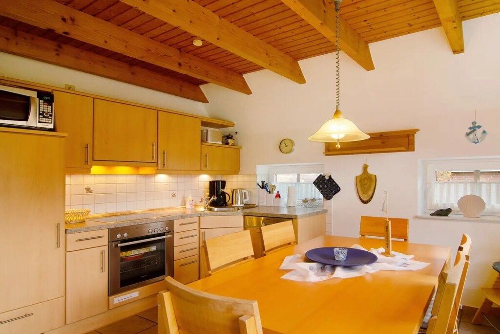 A kitchen with wooden cabinets, a stove, and a dining table with chairs.