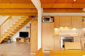 A kitchen with wooden cabinets, a microwave, and a stove. - Holiday home with 3 bedrooms (Neßmersiel)