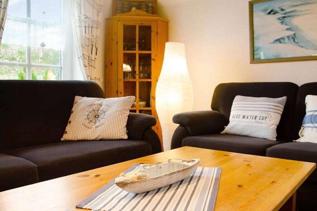 En stue med sofa, lænestole, et træskab og et bord med en dekorativ skål.