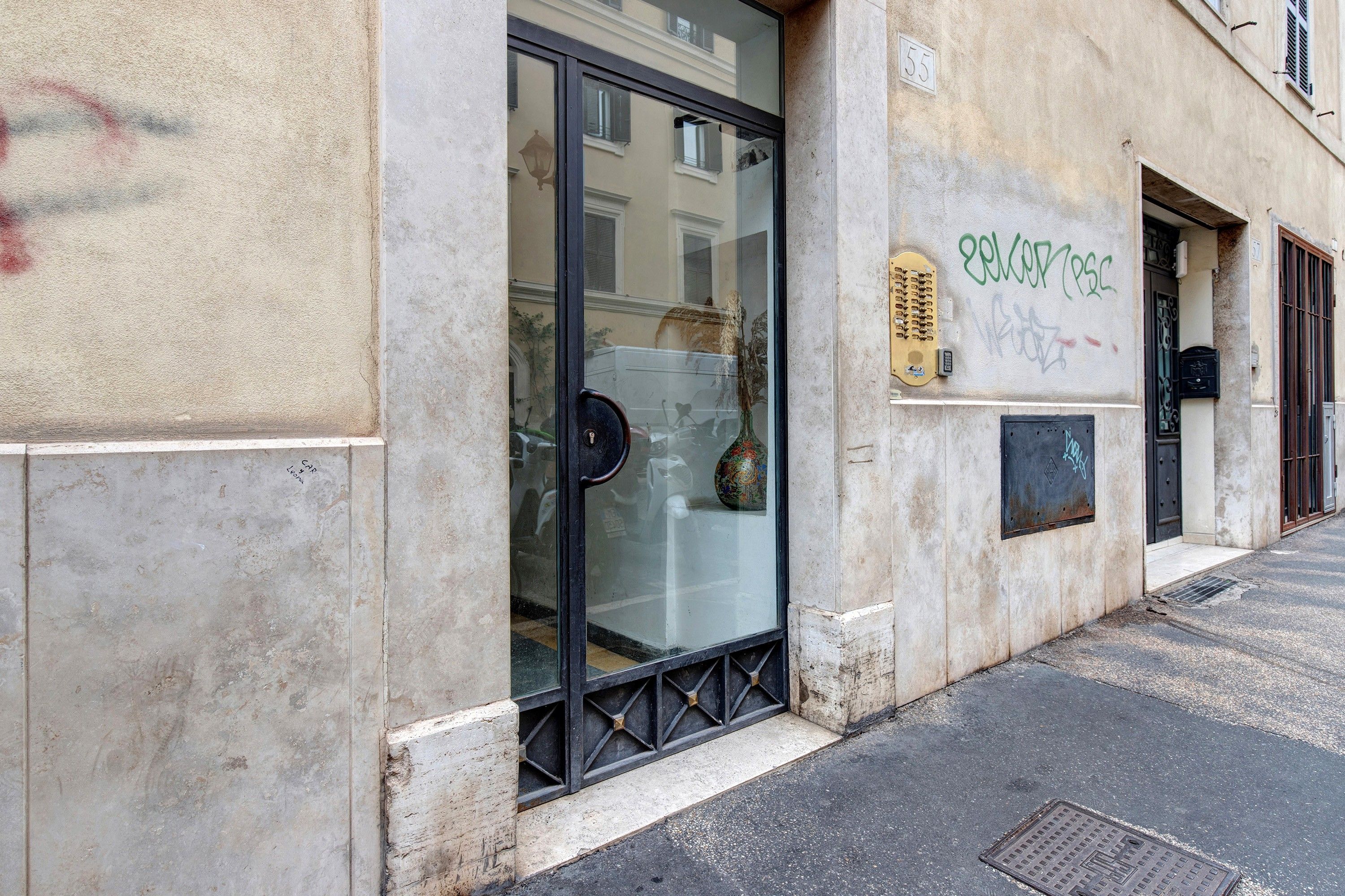 A building facade with a glass door entrance, a metal gate, and a wall with graffiti.