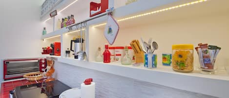 A kitchen with a red toaster, a white kettle, and various kitchen utensils on the counter.