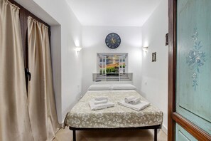 Ein Schlafzimmer mit einem Bett, einer Uhr, einem Fenster mit Ausblick und einer Tür.