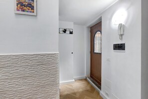 A hallway with a textured wall, a wooden door with a window, and a wall-mounted phone. - Apartment 'Colosseum From Flavio Rome Historic' with Private Garden, Wi-Fi and Air Conditioning (Roma)