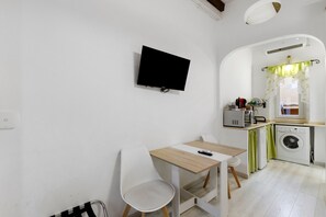 A compact kitchen with a washing machine, a small table, and a chair. - Apartment 'Stay in The Heart Of Rome' with Wi-Fi and Air Conditioning (Roma)