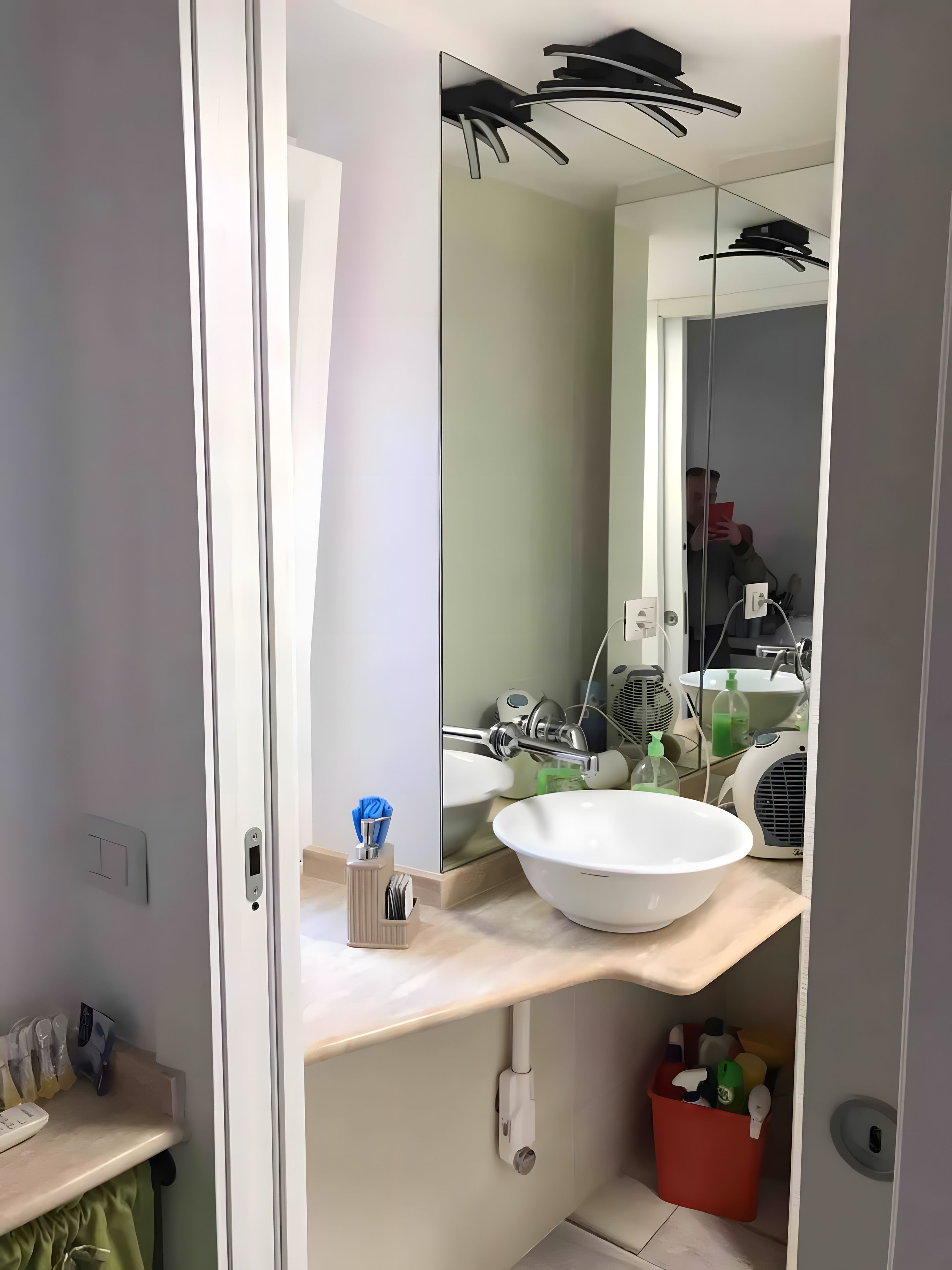 A modern bathroom with a large mirror, a white sink, and a towel rack.