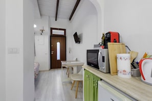 A compact kitchen with a microwave, a coffee maker, and a toaster. There's a dining area with a table and chairs. - Apartment 'Stay in The Heart Of Rome' with Wi-Fi and Air Conditioning (Roma)