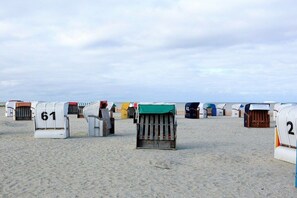 Strandhütten mit den Nummern 61 und 2, ordentlich in Reihen an einem Sandstrand aufgereiht.