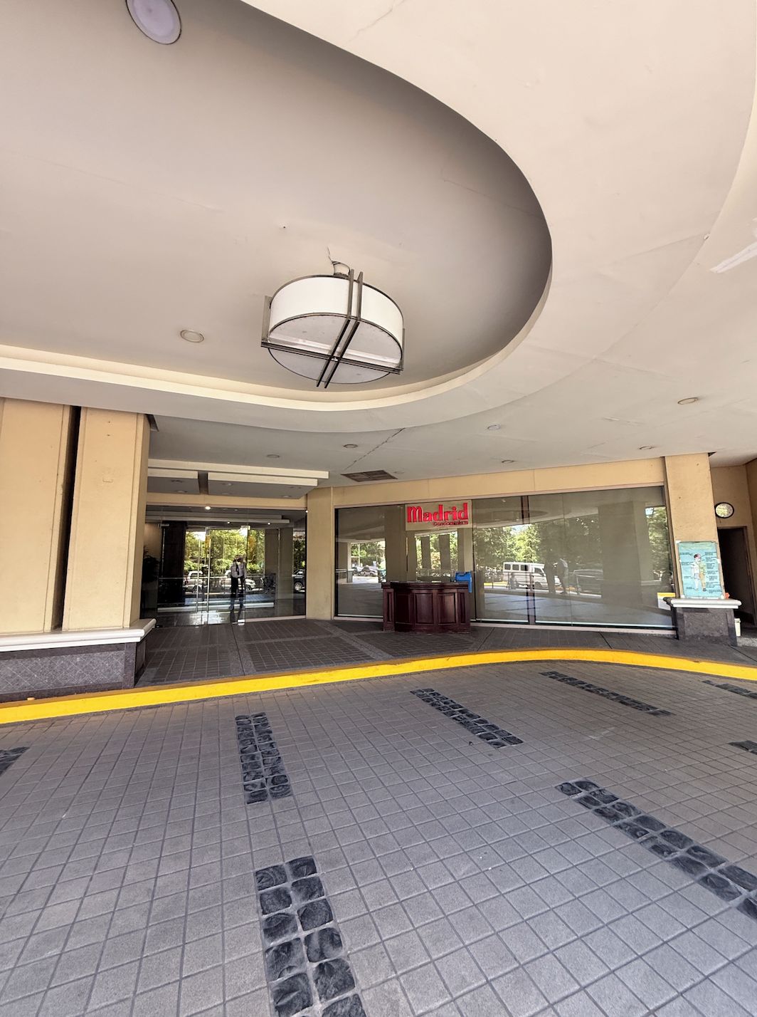 Entrada de un edificio con puerta de vidrio, un mostrador de recepción y un letrero que dice 'Madrid'.