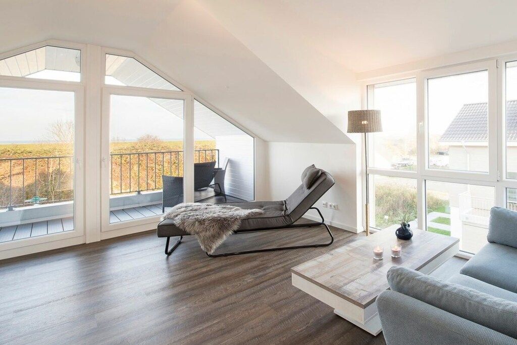 A modern living room with a large window, a lounge chair, a sofa, and a coffee table.