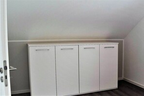 Ein weißer Kleiderschrank mit vier Türen in einem Raum mit schräg versetzter Decke.